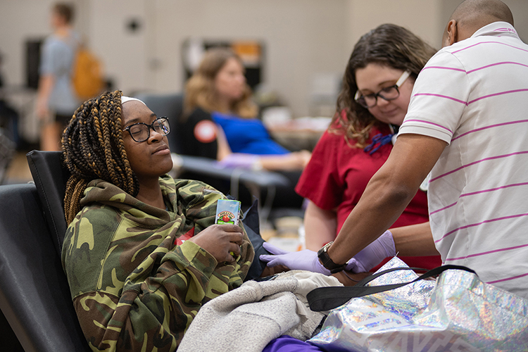 MTSU student Pinkie Fossett, left, relaxes while American Red Cross workers pamper her during her blood donation Monday, Nov. 18, at MTSU's 2019 "Bleed Blue, Beat WKU" blood drive in the Campus Recreation Center. Fossett and 396 other successful MTSU community donors helped the university win the friendly competition for the third straight year and the seventh time since 2010. (MTSU photo by James Cessna)