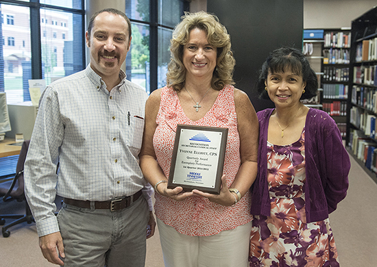 Yvonne Elliott, shown at center, executive aide in MTSU's Center for Popular Music, displays the plaque she received Aug. 15 as the university’s first Quarterly Secretarial/Clerical Award winner for the 2014-15 academic year. Celebrating with Elliott are Dr. Greg Reish, left, the new director of the Center for Popular Music, and Dr. Zeny Panol, associate dean of the College of Mass Communication, which houses the center. (MTSU photo by Andy Heidt)
