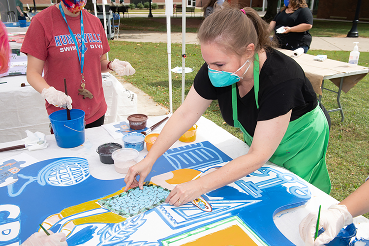 MTSU art education professor Debrah Sickler-Voigt adjusts the template for a planned mosaic on an oversized wooden puzzle piece for "creativity" during an outdoor "Pop-Up Mural Event" in September on campus. The 10 different handcrafted puzzle pieces, now on display, are part of a public art project collaboration between the College of Liberal Arts and the College of Basic and Applied Sciences to show students the skills they need for success. (MTSU photo by James Cessna)
