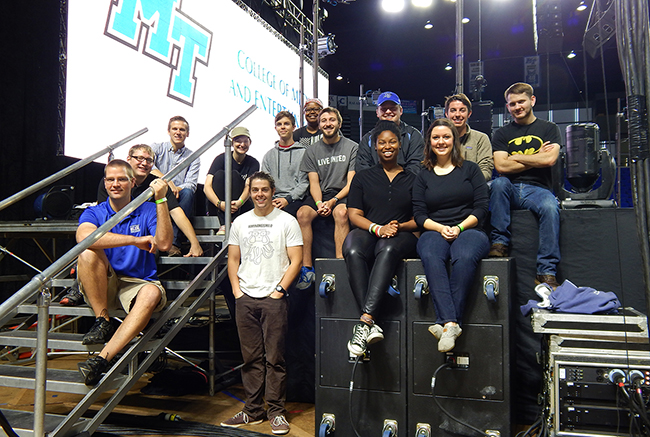Mike Forbes, seated at front left, assistant director of technologies for MTSU's College of Media and Entertainment, is joined by his Video Technology class students on stage in Murphy Center early Oct. 1 in front of the customized 30-foot-by-20-foot video wall they created for the Homecoming 2015 concert featuring Icona Pop. Shown on the front row with Forbes are senior electronic media communication majors Paul Douglas, Angie Carter and Adrienne Kelley. Seated on the stairs and in the second row are, from left, junior EMC majors Zack Johnson, Barrett Depies and Sara Daily; senior EMC majors David Marrow and Robbie Weaver; junior EMC major Sokoya Crockett; seniors Wes Jenkins and Trevor Ball and junior Alex Briley. (MTSU photo by News and Media Relations)