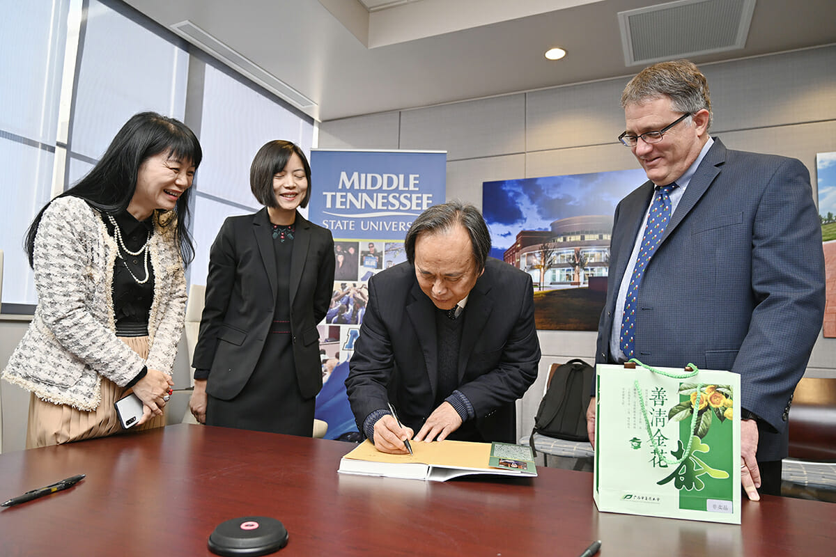 Guangxi University researcher Jiagang Deng, center right, autographs a copy of the book “Medicinal Study of Agricultural Residues I” that he presented Dec. 17 to MTSU Provost Mark Byrnes, right, as colleagues Xiaotao Hou of Guangxi University, left, and MTSU’s Iris Gao observe. Deng, who wrote the book with members of his research team, also presented Byrnes with Chinese herbal tea from Guangxi University of Chinese Medicine. (MTSU photo by Andy Heidt)