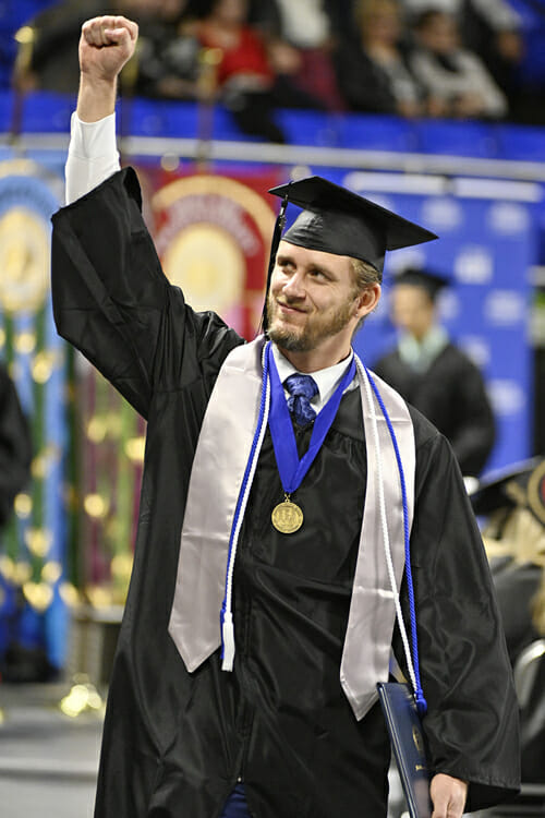 A graduating MTSU student, prized diploma in hand, salutes a supporter in the Murphy Center crowd Saturday, Dec. 15, during the university’s fall 2018 morning commencement ceremony. (MTSU photo by Andy Heidt)
