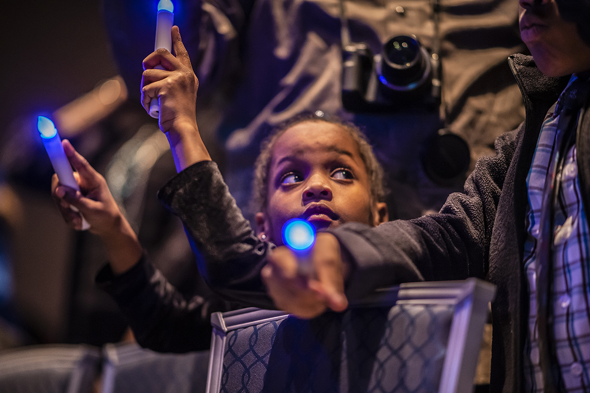 A young attendee holds two electronic blue candles during MTSU’s 2019 MLK Candlelight Vigil Monday night inside the Student Union Ballroom. (MTSU photo by Eric Sutton)