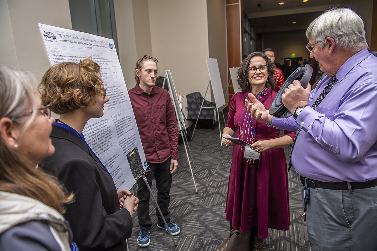 MTSU’s Neal McClain, right, a director of the computer science lab in the James E. Walker Library, helps explain the “Augmented Reality to Improve Student STEM Success” research project to Ilana Horn, professor of mathematics education at Vanderbilt University’s Peabody College, in February 2019 on Day 1 of the Tennessee STEM Education Center’s 13th annual research conference in the Student Union Building. Listening are McClain’s faculty and student partners in the project: professor Amy Phelps, left, Myranda Uselton and Levi Madden. The 2020 conference will be Jan. 16-17 at Tennessee Tech in Cookeville, Tenn. (MTSU file photo by Eric Sutton)