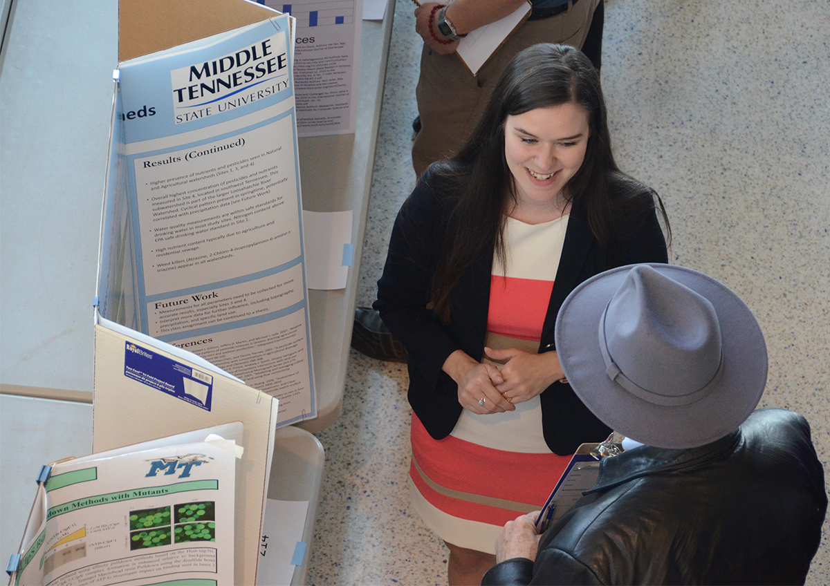 Miranda McBride, 24, an MTSU geosciences graduate student from Nashville, Tenn., answers questions from judge Pete Neff, an aerospace professor, Tuesday (March 19) during the College of Basic and Applied Sciences Scholars Day poster session in the Science Building atrium. 