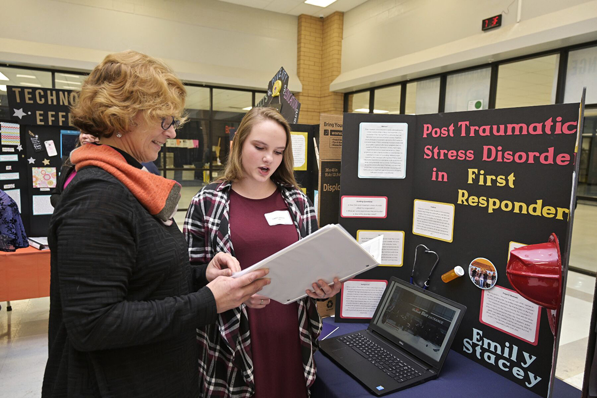 Blackman High School chemistry and physics teacher Kim Baumann, left, listens as senior Emily Stacey shares details about her “PTSD in First Responders” capstone research project March 4 in the school’s cafeteria. Stacey said she plans to attend MTSU and major in counseling and minor in psychology. (MTSU photo by Andy Heidt)