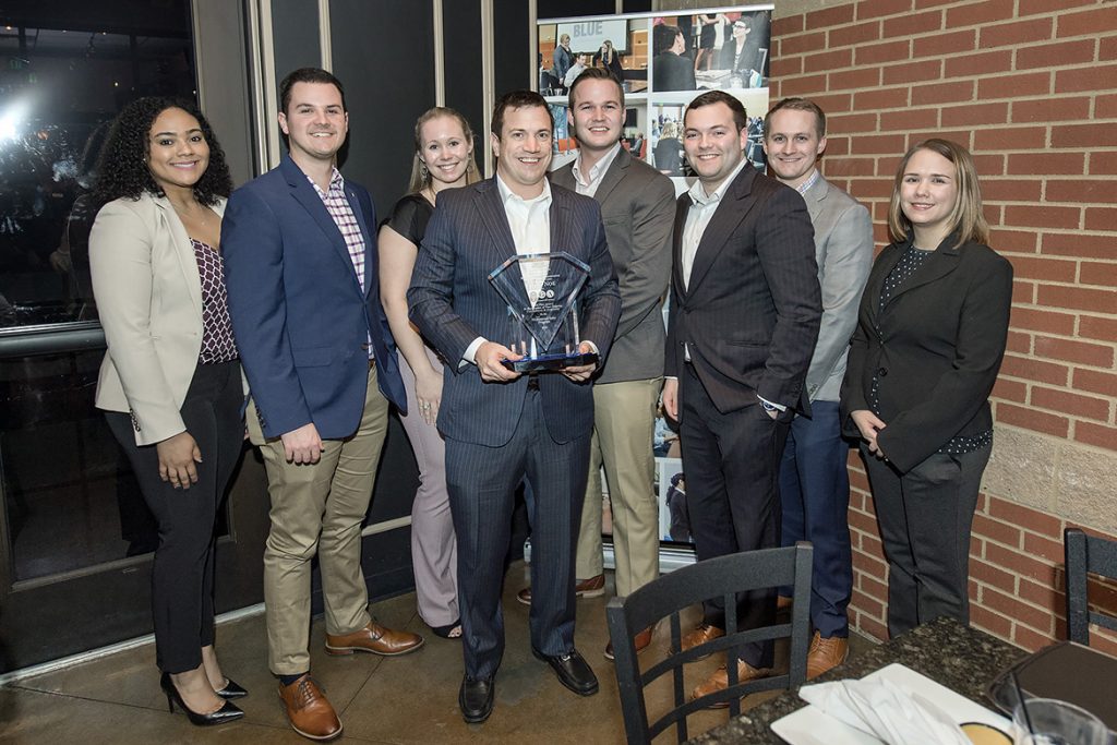 Jamie Noe, center holding award, owner and founder of Insurance Group of America, is pictured with several of MTSU alumni who now work for his company during the February MTSU Professional Sales Program Advisory Board meeting at Jonathan's Grille in Murfreesboro. Noe, also an advisory board member, was honored for IGA’s $100,000 contribution the program. Pictured, from left, are Taylor Adams, Logan Glasscock, Brittany Millard, Noe, Charlie Myers, Matthew Reynolds, Justin Black and Allison Lyons. (MTSU photo by Andy Heidt)