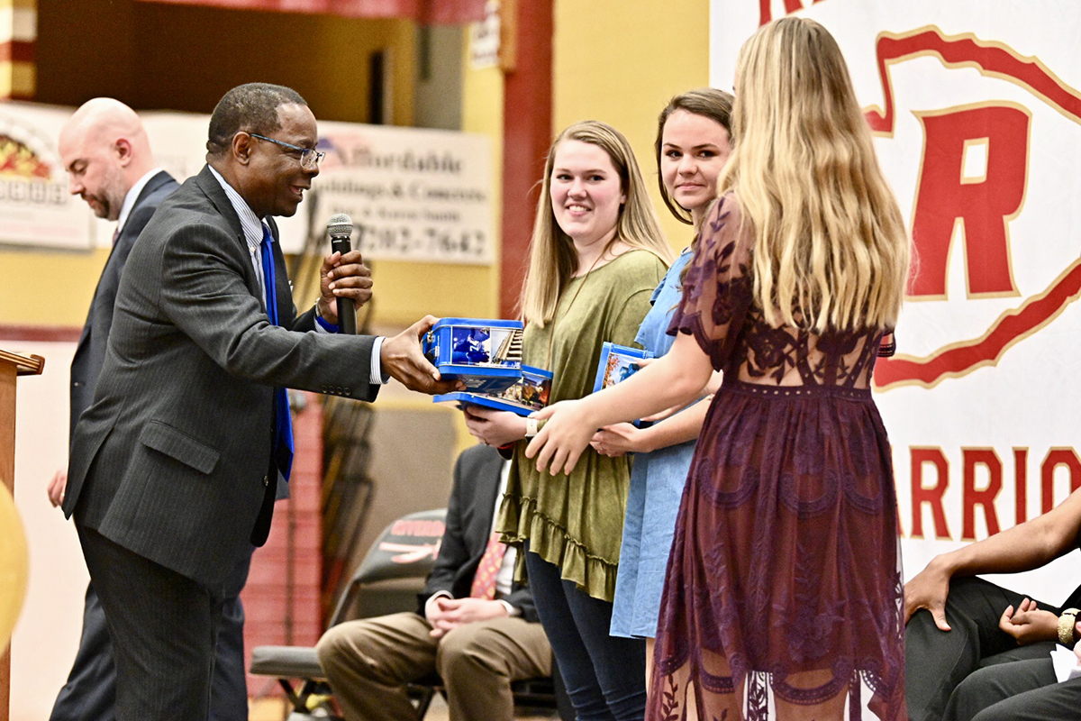 MTSU President Sidney A. McPhee, second from left, gives commemorative lunch boxes to Riverdale seniors Lindsay Smith, center, Megan Lawrence and Destiny Juliano Friday (April 5) at the first Riverdale College and Career Signing Day in the Johnny Parsley Memorial Gym. 