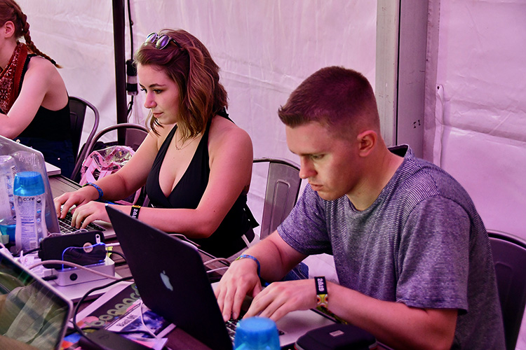 MTSU journalism students Megan Cole, left, and Tyler Lamb work on stories Saturday from the MTSU Bonnaroo campus. (MTSU photo by Andrew Oppmann)