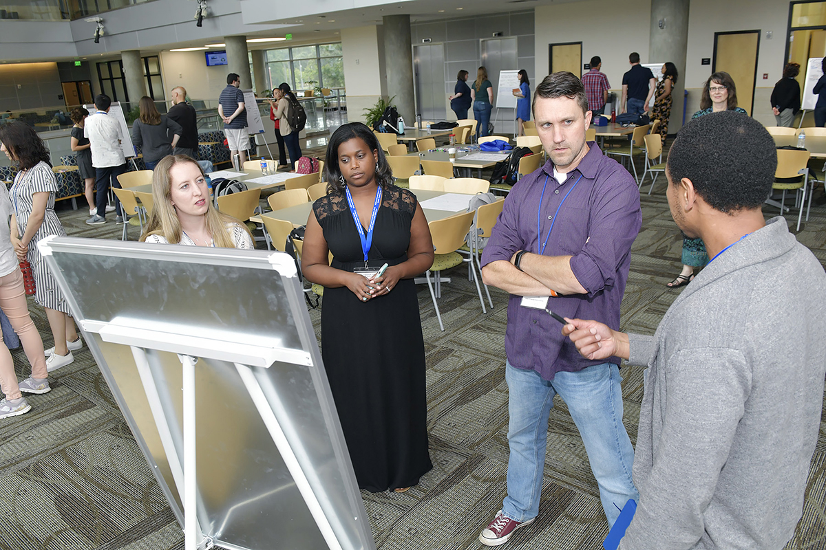 Emma Goodwin, left, of Portland (Oregon) State University, MTSU’s Angela Google and MTSU biology education faculty member Grant Gardner listen to Lashawn McNeil of the University of Georgia explain his doctoral research during a June 6 poster session in the Science Building. A combined 32 grad students and mentors attended the 2019 Sandra K. Abell Institute. (MTSU photo by Andy Heidt)