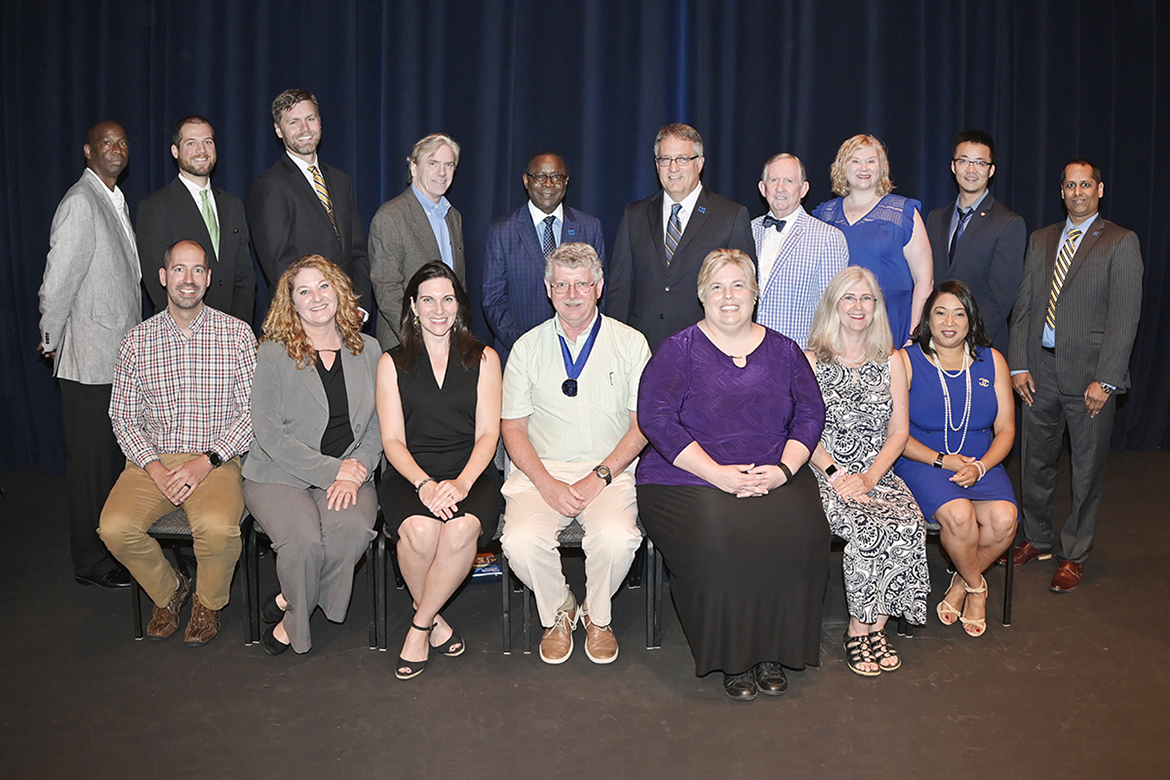 MTSU faculty members gather for a group photo with university leaders Thursday, Aug. 22, after they were recognized by the MTSU Foundation with awards for their service at the Fall Faculty Meeting in Tucker Theatre. The recipients and their 2019 honors include, seated front row from left, history professor Andrew Polk, Outstanding Teaching Award; Cynthia Allen of the Department of Environmental Health and Safety, Outstanding Public Service Award; English professor Kate Pantelides, Outstanding Teaching Award; physics professor William Robertson, Career Achievement Award; marketing professor Diane Edmondson, Outstanding Public Service Award; French language professor Joan McRae, Outstanding Achievement in Instructional Technology Award; mathematics professor Christina Cobb, Outstanding Teaching Award. Standing from left are history professors Aliou Ly, Outstanding General Education Award, and Andrew Fialka, Outstanding Achievement in Instructional Technology Award; Department of University Studies professor Ryan Korstange, Outstanding Achievement in Instructional Technology Award; media arts professor Tom Neff, Special Projects Award; MTSU President Sidney A. McPhee, University Provost Mark Byrnes and MTSU Foundation President Ron Nichols; communication studies professor Mary Beth Asbury, Outstanding Teaching Award; agriculture professor Song Cui, Distinguished Research Award; and engineering technology professor Vishwas Bedekar, Outstanding Teaching Award. Not pictured is history professor Carroll Van West, director of the MTSU Center for Historic Preservation, who received an Outstanding Public Service Award. Click on the photo for details on each of the professors’ accomplishments. (MTSU photo by Andy Heidt)