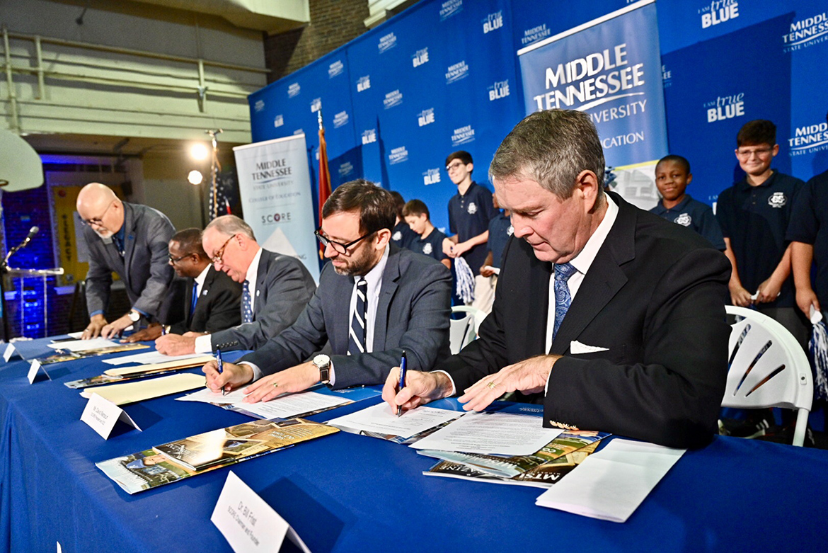 Pictured, from far left standing, is Andrew Oppmann, MTSU vice president for marketing and communications; seated, from left, are MTSU President Sidney A. McPhee; MTSU Board of Trustees Chairman Stephen Smith; SCORE President and CEO David Mansouri; and former U.S. Senate Majority Leader Bill Frist, SCORE founder and chairman. Middle Tennessee State University and SCORE (State Collaborative on Reforming Education) signed an agreement Wednesday, Aug. 28, that seeks to improve teacher training within the university’s College of Education. The signing was held at Homer Pittard Campus School, a K-5 teaching laboratory school owned by MTSU and operated by Rutherford County Schools. In the background are some of the dozens of students that attended the signing. (MTSU photo by J. Intintoli)