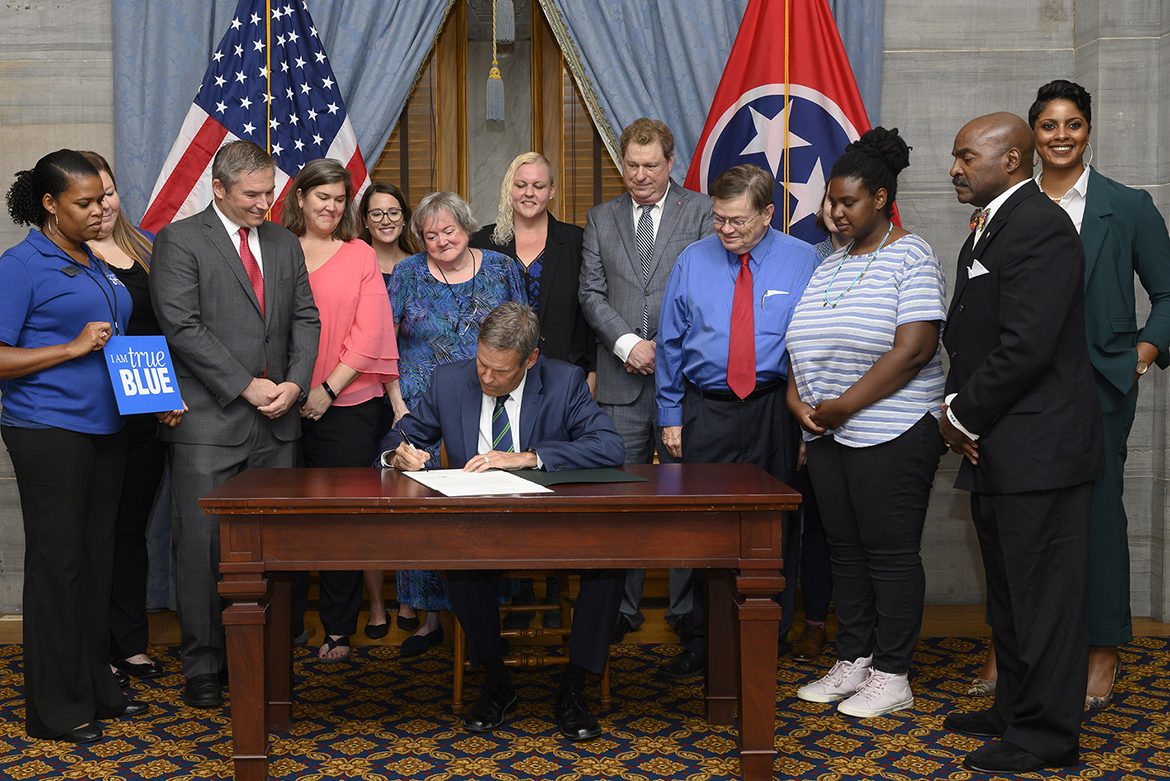 Tennessee Gov. Bill Lee, seated, conducted an official signing ceremony Aug. 20 for a new law to require state-supported colleges and universities to develop programs to help homeless students. Attending the signing are MTSU’s Danielle Rochelle, far left, coordinator of outreach and support programs for MT One Stop; and next to her, Becca Seul, associate director at MT One Stop at MTSU. They were among several stakeholders, including state lawmakers and representatives from area educational institutions and nonprofits, also pictured and who advocated for the legislation. (Photo courtesy of Joy Kimbrough/Office of Gov. Bill Lee)