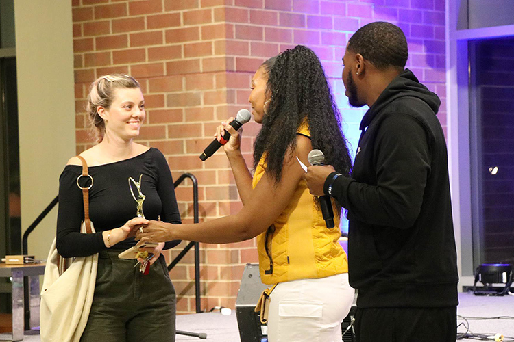 Rep Your Roots second place winner Julia Cooper, left, accepts her trophy at this year’s talent showcase held Friday, Sept. 20, in the Student Union atrium. Cooper, a junior in the College of Media and Entertainment, sang an original acoustic song title “Footprints.” (Submitted photo)
