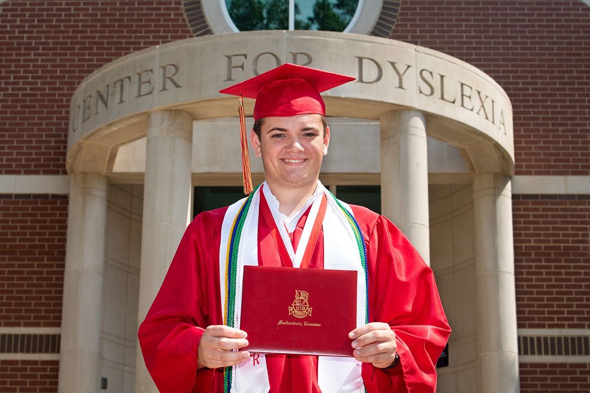 Aaron Lile poses outside the Tennessee Center for the Study and Treatment of Dyslexia in the academic regalia he wore at his 2019 graduation as salutatorian of Riverdale High School in Murfreesboro. (MTSU photo by James Cessna)