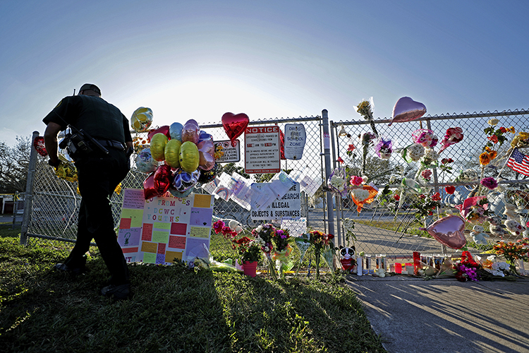 A Broward County Sheriff's Office deputy removes police tape from a makeshift memorial at Marjory Stoneman Douglas High School in Parkland, Fla., Sunday, Feb. 18, 2018, four days after a former student went on a shooting spree at the school, killing 17 and injuring 17 more. Three staffers from the South Florida Sun Sentinel will discuss the paper’s 2019 Pulitzer Prize for public service journalism at MTSU Tuesday, Oct. 22. (John McCall/South Florida Sun Sentinel)