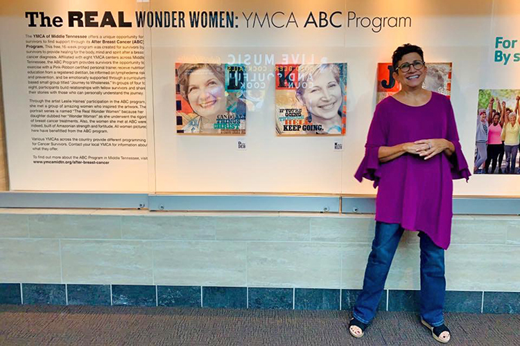 Leslie Haines, a visual communication professor in the MTSU School of Journalism and Strategic Media and breast cancer survivor, poses in front of her work at the Nashville International Airport in September for a special reception for her art exhibit on display. Haines created a series of 12 portrait illustrations of fellow breast cancer survivors titled "The Real Wonder Women: YMCA ABC Program" that will be on display until late February. (Submitted photo)