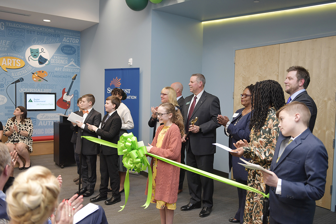 Students, representatives and sponsors of Junior Achievement of Middle Tennessee cut the ribbon Tuesday, Jan. 14, at a grand opening and ribbon-cutting ceremony for the new JA Finance Park on Powell Place in Nashville, Tenn. The new park provides a real-world simulation for students to learn how their financial decisions regarding higher education, health care and other areas affect their personal budgets. MTSU alumna, trustee and JA board member Pam Wright funded an MTSU-branded room in the park. (MTSU photo by James Cessna)
