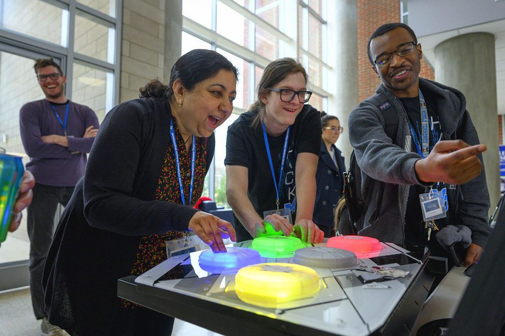 MTSU computer science Chair Medha Sarkar, left, and then-graduate student Steven Sheffey enjoy competing in one of the Infinity team’s games they created during the 36-hour HackMT in the Science Building’s first-floor atrium in January 2020. MTSU team member and current student Myles Chisholm, right, assists. More than a dozen teams will compete in this year’s event, which will be held Jan. 28-30 at MTSU. (MTSU file photo by Cat Curtis Murphy)