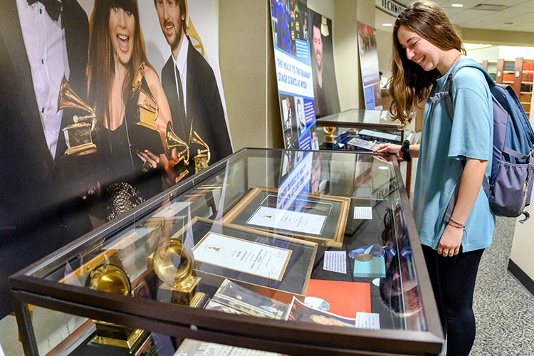 MTSU freshman global studies major Maggie Dennis of Christiana, Tenn., learns more about the MTSU students, alumni and faculty connections to the Grammy Awards while inspecting a display case in an exhibit at the university's James E. Walker Library, “A Legacy of Excellence: MTSU at the Grammys." The exhibit is on display through February. (MTSU photo by J. Intintoli)