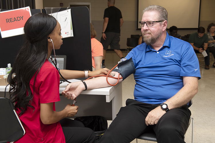 Ray Wiley, associate director of MTSU Campus Recreation and a longtime American Red Cross volunteer, listens as Red Cross employee Kenedra Baugh checks his vital signs before he donates blood at the university's September 2019 "Battle of the Branches" blood drive. MTSU is sponsoring its 2020 valentine blood drive on Monday, Feb. 10, from 10 a.m. to 4 p.m. in Room 322 of the Keathley University Center. (MTSU file photo by James Cessna)