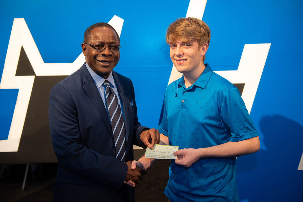 MTSU President Sidney A. McPhee, left, receives a check for $740 from Nathan Lathrop of Chattanooga, Tenn., Monday, Feb. 17, as a donation to the Raider Relief fund to assist with Hurricane Dorian disaster efforts in the Bahamas, McPhee’s native country, in the Student Union Ballroom. Lathrop and four friends who are Center for Creative Arts classmates held a yard sale to raise the money. Lathrop, who plans to start at MTSU in August, attended the MTSU Celebration of Scholars event. (MTSU photo by James Cessna)