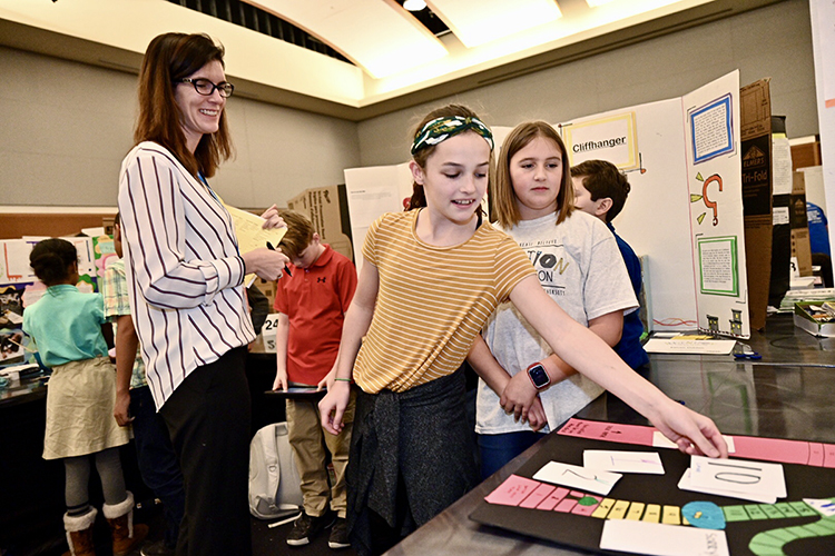 Trisha Ambrose of Accenture Inc., left, a guest judge at MTSU’s 28th annual Invention Convention, listens closely as West Elementary fifth grader Kendall Bucher explains her and classmate Addy Embry's game, "Minister's Cloak," at the event held Feb. 27 at MTSU. Bucher and Embry were among 828 young Middle Tennessee inventors who brought games and solutions to "make life easier" to present and demonstrate to judges for ribbons, trophies and plenty of praise. (MTSU photo by J. Intintoli)
