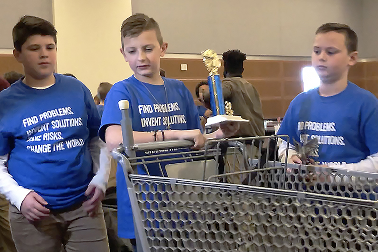 Siegel Elementary fifth-graders Tripp Houston, left, Gabe Cops and Asher Evans prepare to demonstrate their trophy-winning invention, the "Shopper Stopper," to a Murfreesboro CityTV reporter at the 28th annual Invention Convention held Feb. 27 at MTSU. The three, who took their division's top "Make Life Easier" prize as well as the event’s “Eagle Award” for best invention, have been invited to the national Invention Convention in June in Michigan. (MTSU photo by Gina E. Fann)