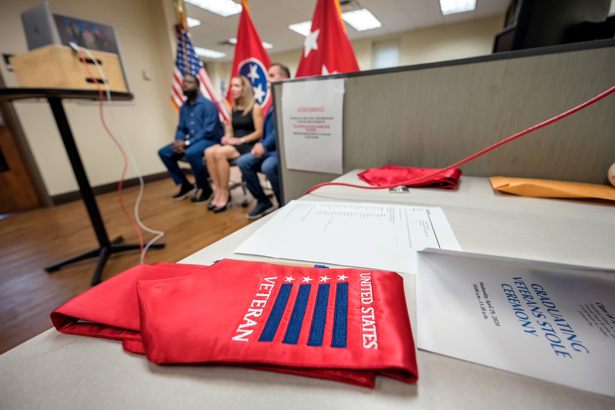 With a red stole and Graduating Veterans Stole Ceremony program in the foreground, Chris Rochelle, left, Hilary Miller and David Corlew watch the virtual ceremony on a computer screen Wednesday, April 29, at the Charlie and Hazel Daniels Veterans and Military Family Center. More than 20 graduating veterans were recognized in the 45-minute ceremony that was broadcast on Facebook Live. (MTSU photo by J. Intintoli)