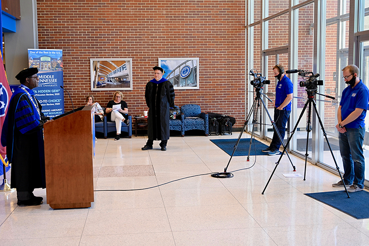 MTSU President Sidney A. McPhee, left, speaks while taping the university's spring 2020 virtual commencement ceremony in the Cope Administration Building to air Saturday, May 9, as university Provost Mark Byrnes, center, awaits his cue to present the degree candidates. Looking on are McPhee's chief of staff Kim Edgar and secretary Elizabeth McClaran, seated, while John Goodwin, second from right, strategic communications manager in the Division of Marketing and Communications, and Joseph Poe, video marketing specialist in the Department of Academic Marketing, record the ceremony for broadcast. MTSU formally presented 2,519 students with degrees in the online event arranged to celebrate their accomplishments during the pandemic. (MTSU photo by Andrew Oppmann)