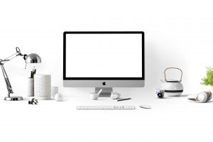 A computer and various desk accessories sit against a white background. 