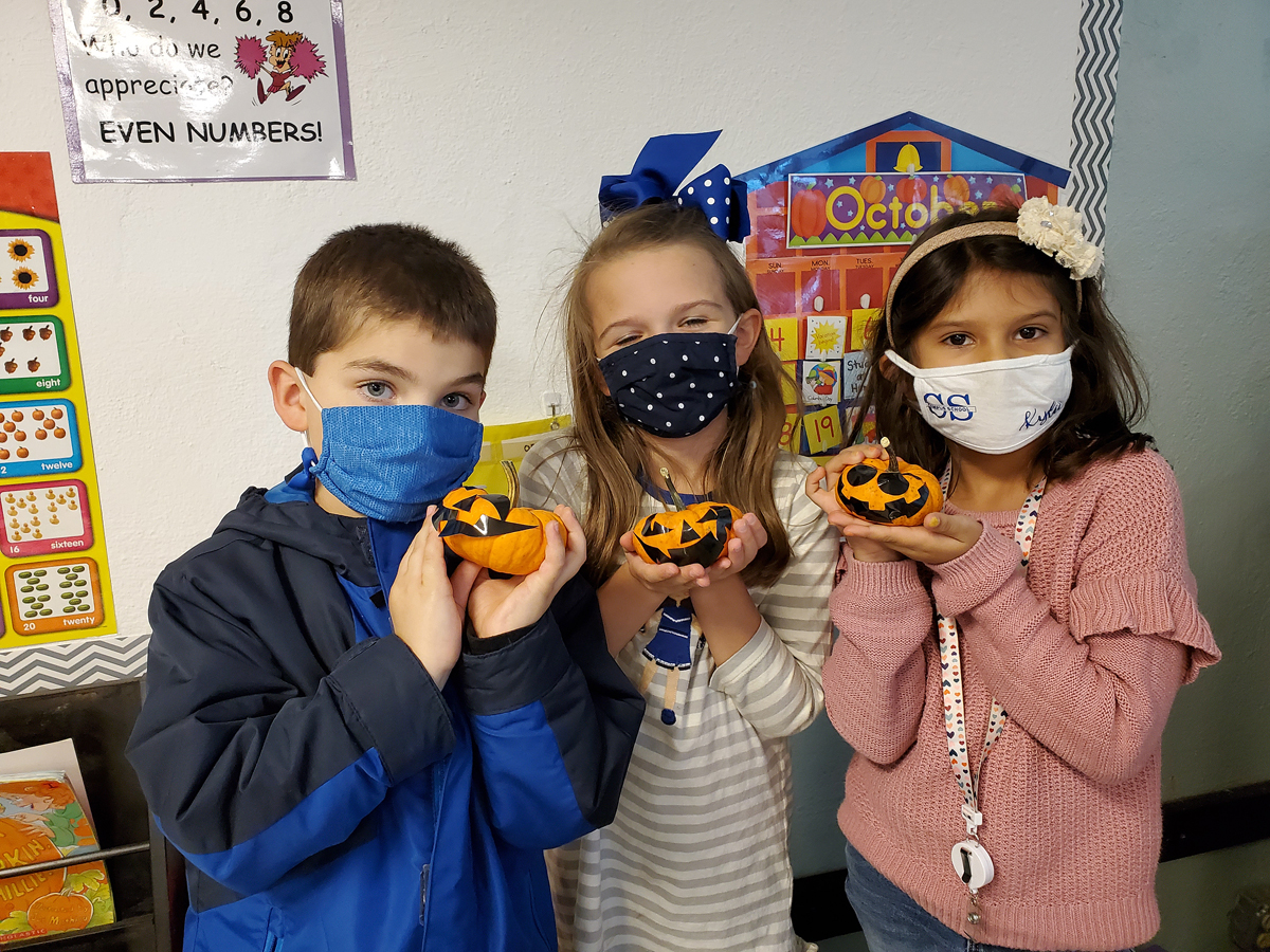 Homer Pittard Campus School first grade students Cooper McDevitt, left, Mary Bryant Vaughn and Kylie Medina display the handheld pumpkins, which were part of the Harvest Handbag items provided by the MTSU agritourism class. Black stickers were included, so the youngsters could make their own pumpkin faces. (Submitted photo by Homer Pittard Campus School)