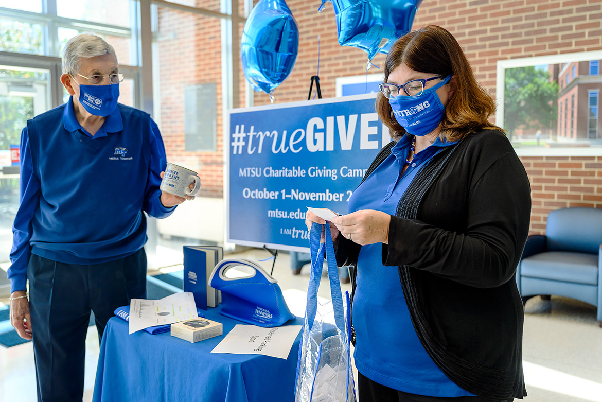 John Hood, left, former state representative and current director of Community Engagement and Support, holds an MTSU coffee mug in the Cope Administration Building atrium as Brenda Wunder, executive secretary for Facilities Services, reads the name of the lucky winner during a weekly Employee Charitable Giving Campaign prize giveaway in late October. (MTSU photo by J. Intintoli)