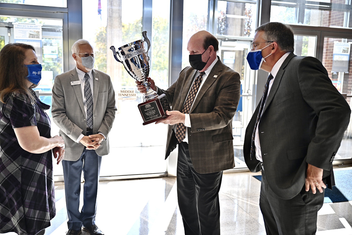 Jones College of Business Dean David Urban inspects the Provost Cup in the atrium of the Cope Administration Building in early November after University Provost Mark Byrnes, right, presented the 2020 cup to the Jennings A. Jones College of Business for having the highest level of participation the 2020 Employee Charitable Giving Campaign. Joining Urban in accepting the award are Teena Young, far left, operations administrator for Jones College, and Associate Dean David Foote. The Jones College won the cup for the eighth straight year. (MTSU photo by Andrew Oppmann)