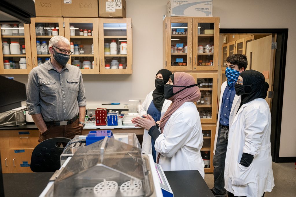 MTSU Department of Biology chair Dennis Mullen, left, talks with the Alnassari family — mom Khadijah, who is a freshman, and triplets Zaynab Alnassari Ahmed and Fatima during a visit to a Science Building lab. The triplets are dual enrollment MTSU students and on a premed pathway. Khadijah Alnassari recently received the 2022 Rutherford ATHENA scholarship she will use to pay MTSU tuition. (MTSU file photo by Andy Heidt)