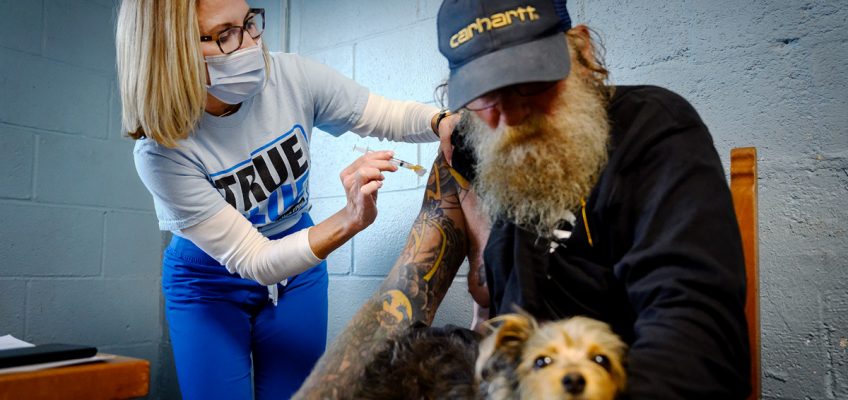 MTSU Health Services RN Tracy Mifflin, left, gives Sonny Bradshaw the one-shot Johnson & Johnson COVID-19 vaccine while he holds his dog, Mizz Peabody. MTSU nurses held a special vaccine clinic Friday, May 28, at Journey Home Inc., a Christian ministry that serves homeless people and the disadvantaged. (MTSU photo by J. Intintoli)