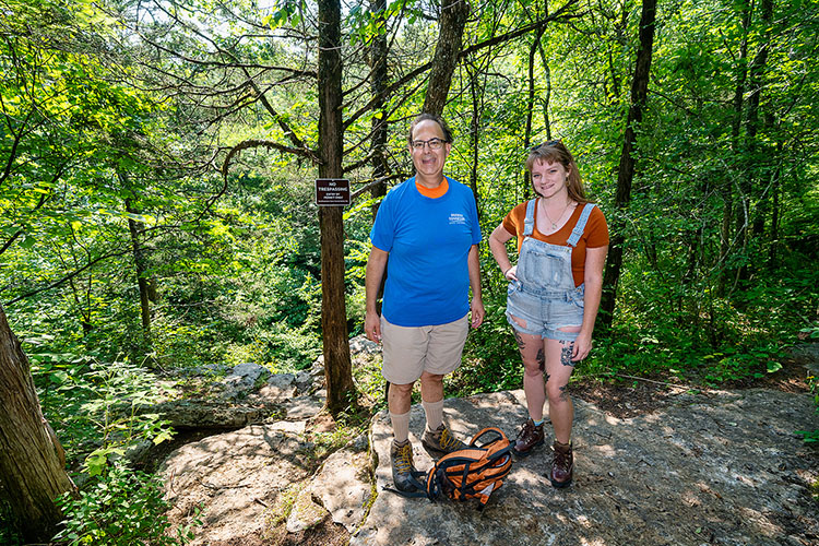 Mark Abolins, Middle Tennessee State University geosciences professor, and Michelle Moore, MTSU undergraduate geosciences student, stand near the sinkhole above of Snail Shell Cave in Rockvale, Tenn., on July 23, 2021. (MTSU photo by Andy Heidt)