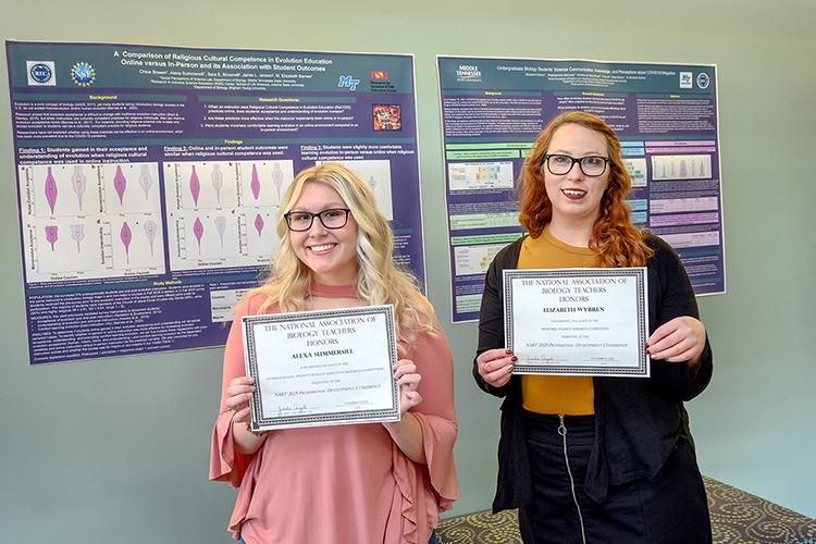 From left, students Alexa Summersill and Elizabeth Wybren show awards they won Nov. 14 at the National Association of Biology Teachers conference in Atlanta for the research posters displayed on the wall behind them in the Science Building. (MTSU photo by J. Intintoli)