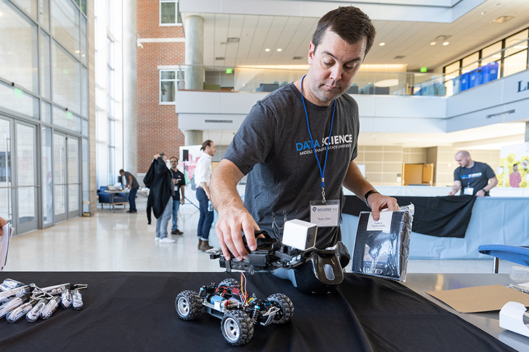MTSU biology professor Ryan Otter, director of the Data Science Institute, inspects one of the model racers that would be competing in the Nov. 13 “AWS DeepRacer” event held in the MTSU Science Building Atrium. The event, which featured five teams racing autonomous racing models, was sponsored by the MTSU Data Science Institute and Amazon Web Services. (MTSU photo by Cat Curtis Murphy)