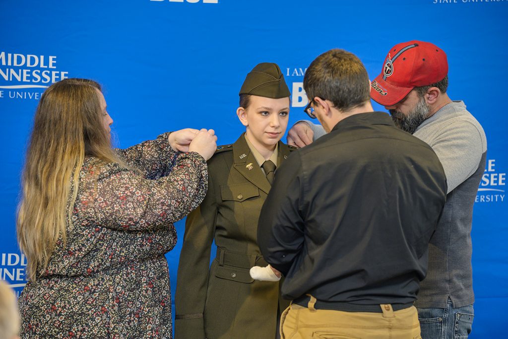 Alana Kassing, center, of Smyrna, Tenn., has her U.S. Army second lieutenant gold bars pinned on her by her mother, Amanda Kassing, left, father, Ricky Kassing, and boyfriend, Bryson Reiter, Friday, Dec. 10, in the Tom H. Jackson Building’s Cantrell Hall. (MTSU photo by Andy Heidt)