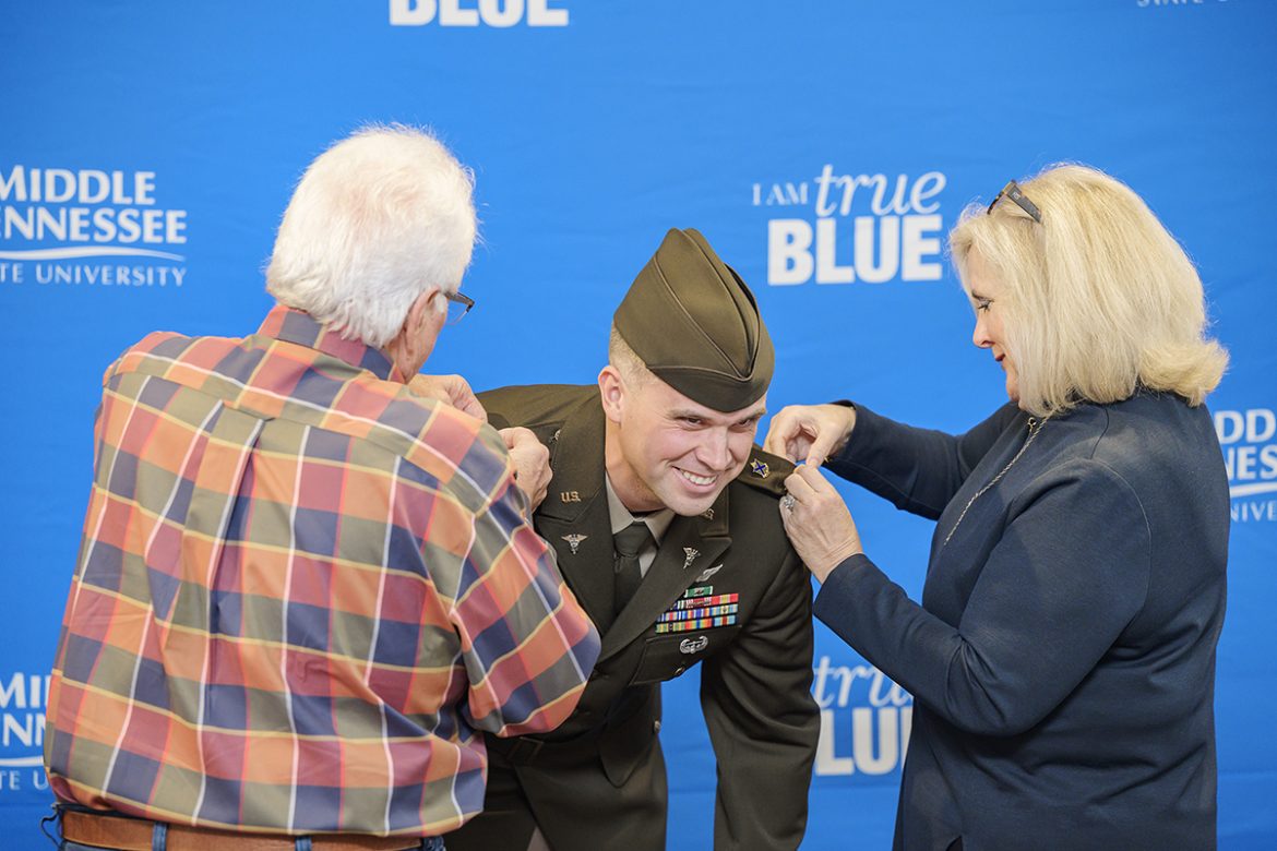New U.S. Army 2nd Lt. Porter Mitchell, center, of Murfreesboro, laughs while being pinned by his parents, David Harbin, left, and Susan Harbin, during the MTSU Blue Raider Battalion Fall 2021 Commissioning Ceremony in Tom Jackson Building’s Cantrell Hall Friday, Dec. 9. Mitchell earned his MBA and will graduate Saturday, Dec. 11. (MTSU photo by Andy Heidt)