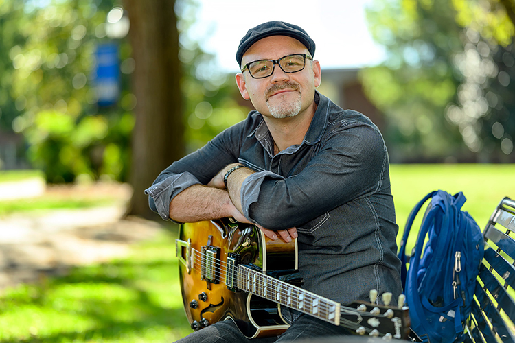 Professional guitarist and student Beau Tackett, a student in the Master of Music program, poses for a photo in Walnut Grove on the MTSU campus. (MTSU photo by J. Intintoli)