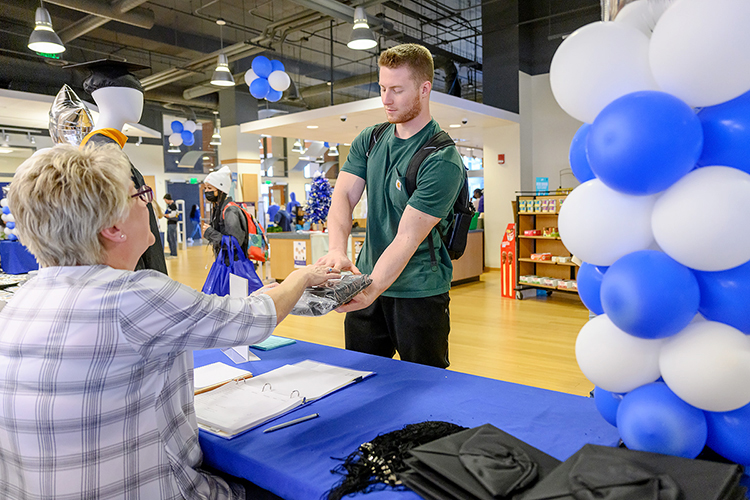 MTSU graduating senior Chad Dunbar, right, a professional pilot major from Appleton, N.Y., accepts his cap and gown from Melisa Warner, assistant manager of Phillips Bookstore, Friday, Dec. 3, during the university's Senior Celebration in the Student Union store. Students graduating Saturday, Dec. 11, in MTSU's fall 2021 commencement ceremonies were able to pick up regalia and learn about the university's Senior Gift Program for scholarships and other development needs, alumni services and career development. (MTSU photo by J. Intintoli)