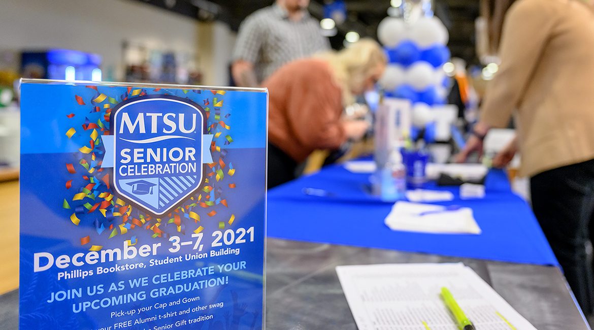 A flyer with information about MTSU's special four-day Senior Celebration sits on a table in Phillips Bookstore inside the Student Union Friday, Dec. 3, as members of the fall Class of 2021 pick up their academic regalia in the background. MTSU will hold its fall 2021 commencement ceremonies Saturday, Dec. 11, in Murphy Center. (MTSU photo by J. Intintoli)