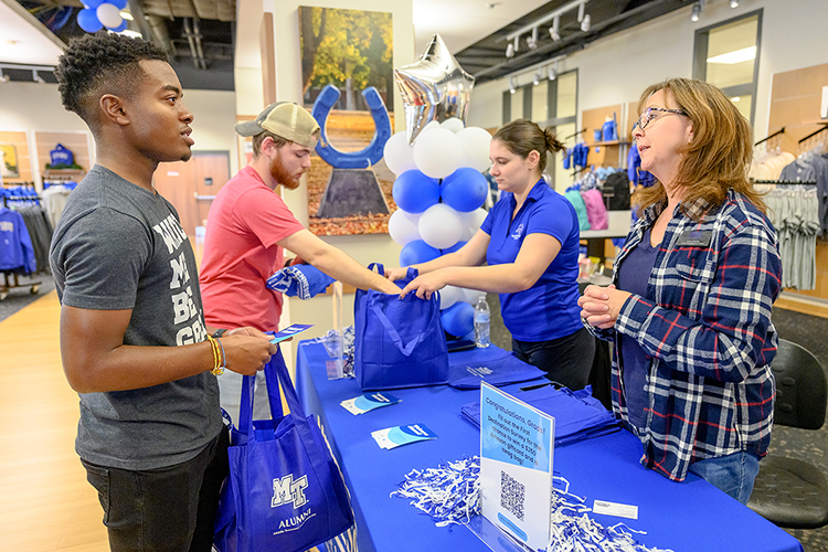 MTSU graduating senior Dylan Bush of Antioch, Tenn., left, who's majoring in the Leisure, Sport and Tourism Management Program, listens carefully to MTSU Career Development Center clerk Amy Medlin, right, as fellow senior and exercise science major Kendall Matchinske of Gallatin, Tenn., center left, helps Jeanette Stevens, an adviser in the Career Development Center, pack up his bag of senior items Friday, Dec. 3, during the university's Senior Celebration in Phillips Bookstore inside the Student Union. Students graduating Saturday, Dec. 11, in MTSU's fall 2021 commencement ceremonies were able to pick up regalia and learn about the university's Senior Gift Program for scholarships and other development needs, alumni services and career development. (MTSU photo by J. Intintoli)