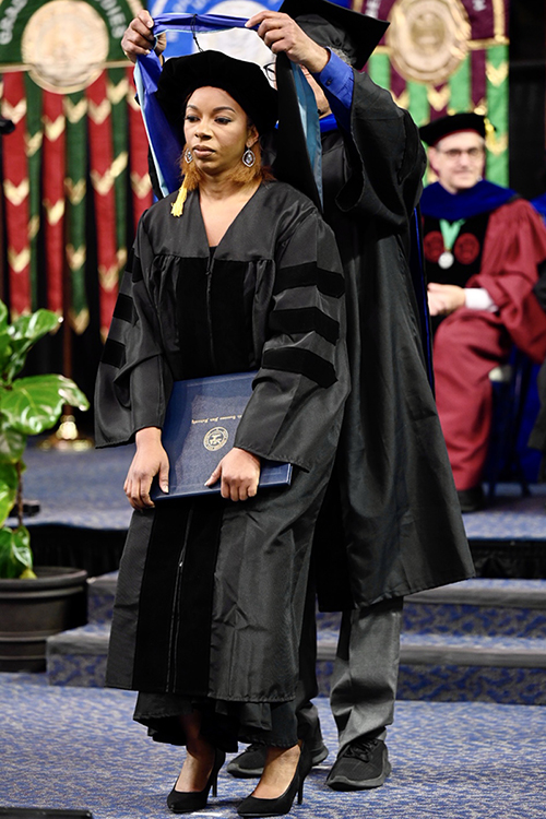 Dr. Brelinda Johnson, manager of the MTSU Scholars Academy, steps forward slightly so her dissertation adviser, Donald Snead, can drape her new doctoral hood across her shoulders Saturday, Dec. 11, during MTSU's fall 2021 commencement in Murphy Center. Johnson earned the university's first doctoral degree aimed at helping college students succeed in MTSU's Assessment, Learning and Student Success Program. (MTSU photo by J. Intintoli)
