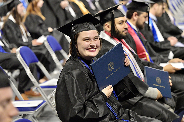 A graduating senior at MTSU's fall 2021 commencement ceremonies holds her new degree tightly as her supporters cheer from the stands in Murphy Center Saturday, Dec. 11, at MTSU's fall 2021 commencement ceremonies. The university presented degrees to more than 1,670 students in three commencement events to conclude the fall semester. (MTSU photo by Andy Heidt)