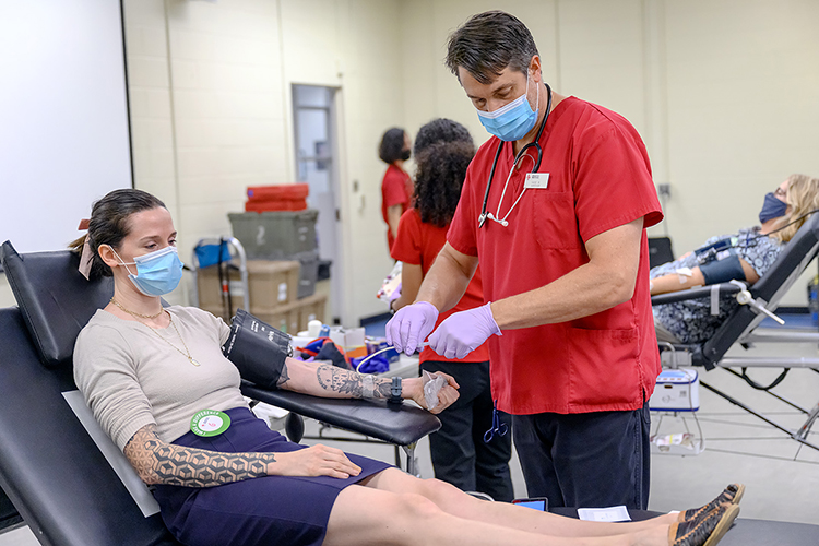 Stephanie Bandel of the Center for Popular Music at MTSU, left, waits to donate blood as American Red Cross phlebotomy supervisor Hans Wayland prepares the equipment in this file photo from the September 2021 MTSU “Battle of the Branches” blood drive in the Keathley University Center. Blood donors can "circulate the love" again at the university's annual valentine blood drive, set Monday, Feb. 7, from 10 a.m. to 4 p.m. in Room 324 in the Keathley University Center, 1524 Military Memorial Drive. (MTSU file photo by J. Intintoli)