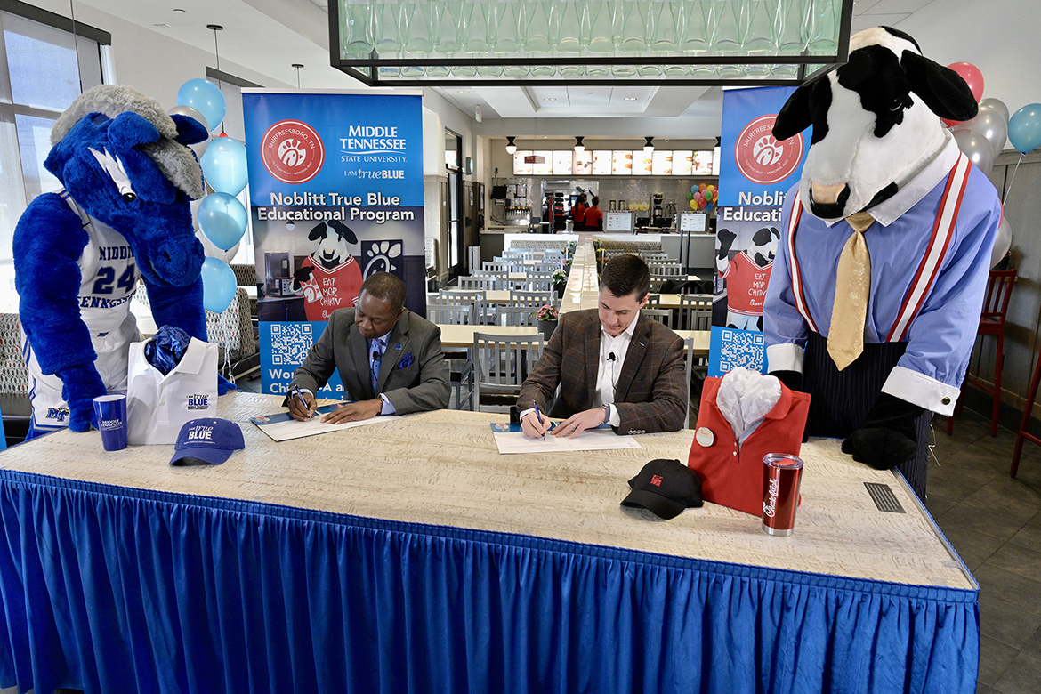 With their respective mascots looking on, MTSU President Sidney A. McPhee, seated left, and Beau Noblitt, restaurant operator for Chick-fil-A Murfreesboro, sign an agreement Wednesday, Jan. 12, at the fast-food chain’s Memorial Boulevard location that provides tuition assistance for qualifying local employees. (MTSU photo by Andy Heidt)