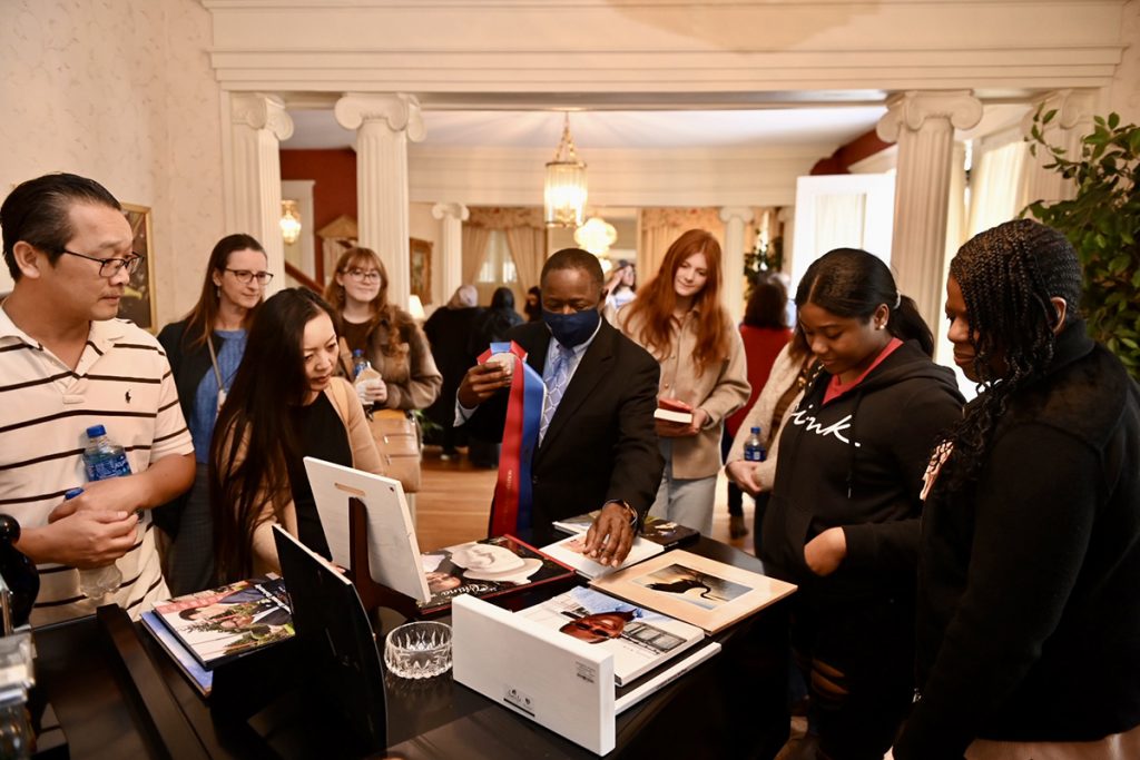 MTSU President Sidney A. McPhee, center, mingles with guests at his home, showing some of the photographs he has taken on past trips to China during the Presidents Day Open House Celebration of Scholars to conclude the visit by high school seniors who have been offered major scholarships by the university. Dozens of potential students and their parents accepted his offer to visit the house at the corner of East Main Street and Middle Tennessee Boulevard. (MTSU photo by James Cessna)